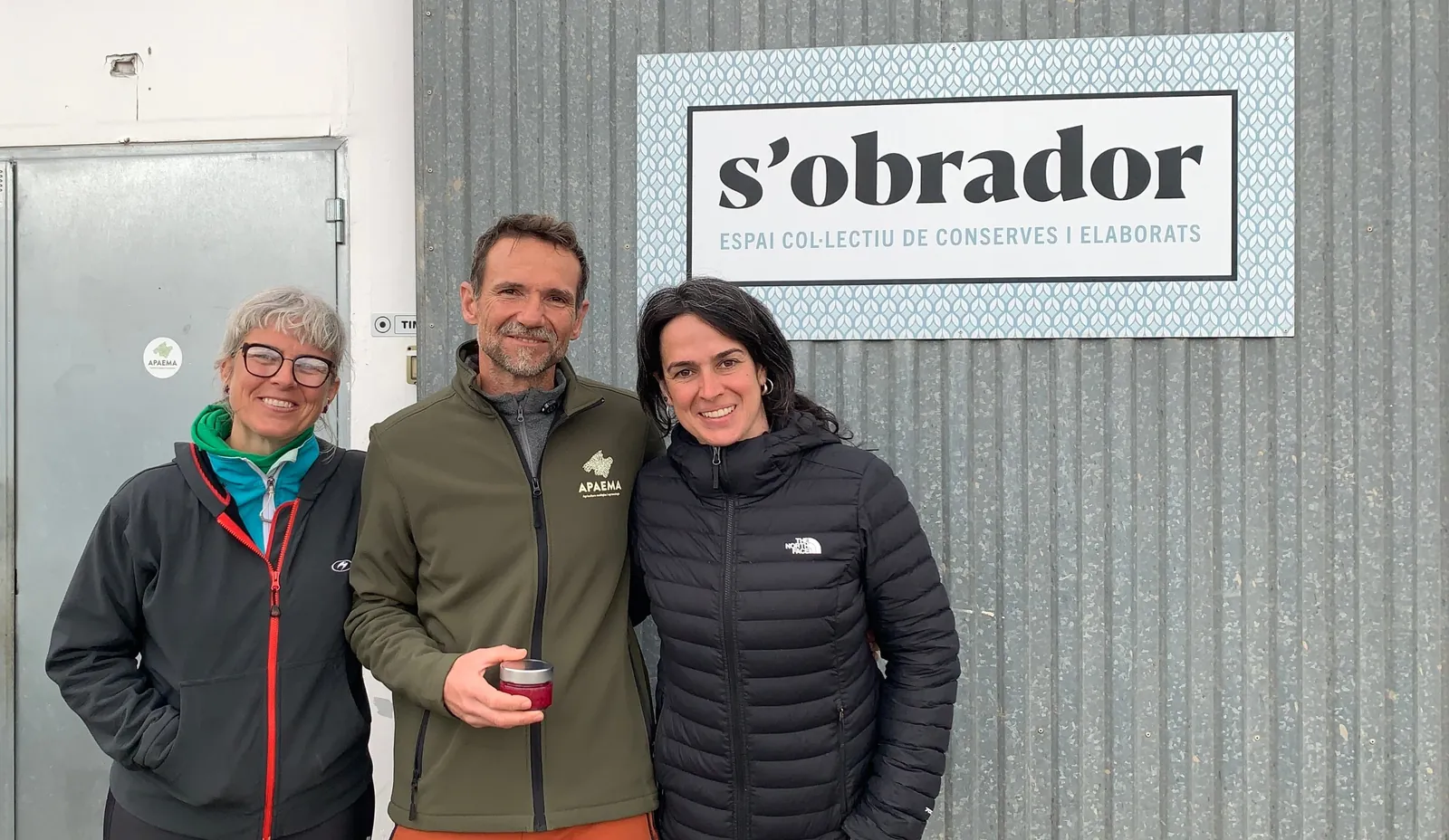 Tres personas posando junto al cartel de S'Obrador