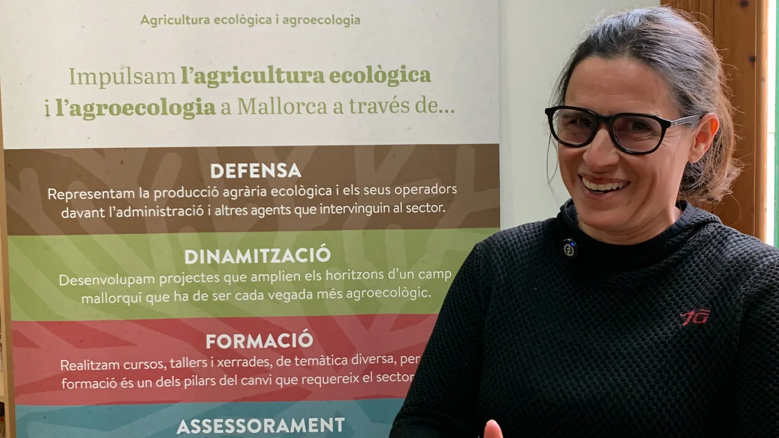 Técnica de APAEMA sonriente frente a un cartel de la asociación