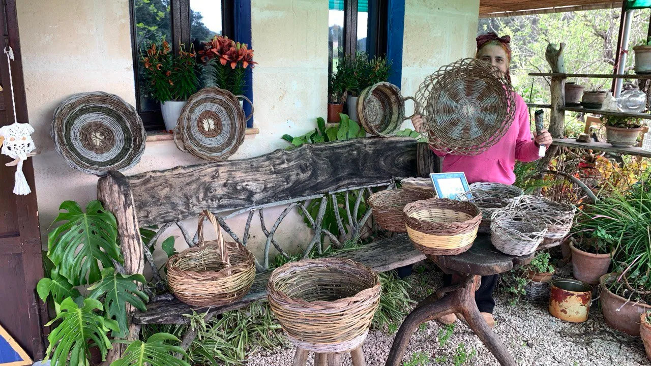 Mujer junto a cestas de fibra vegetal en una terraza llena de plantas