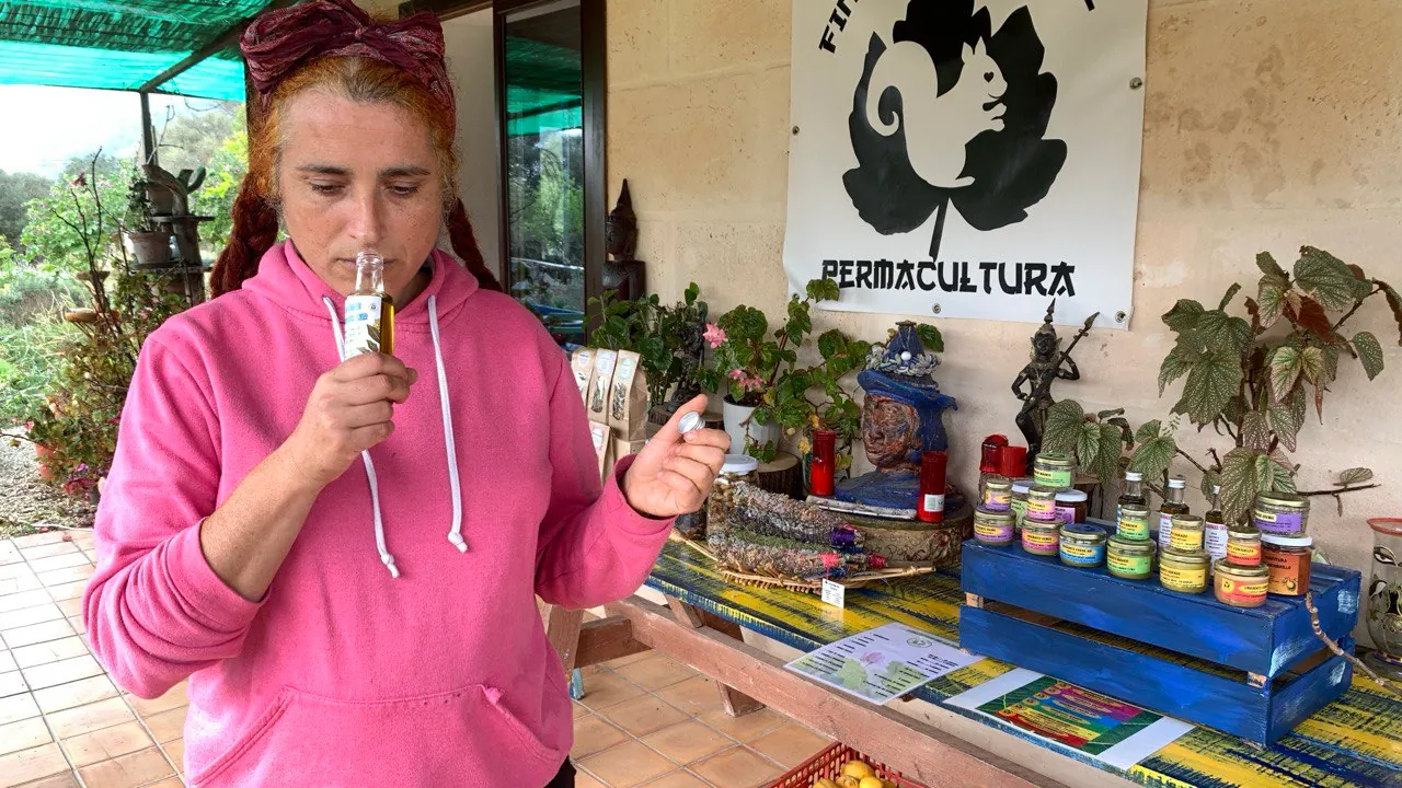 Mujer oliendo un producto junto al cartel de Finca S'Esquirol