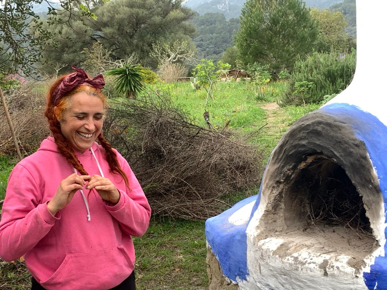 Mujer sonriente junto a un horno de barro