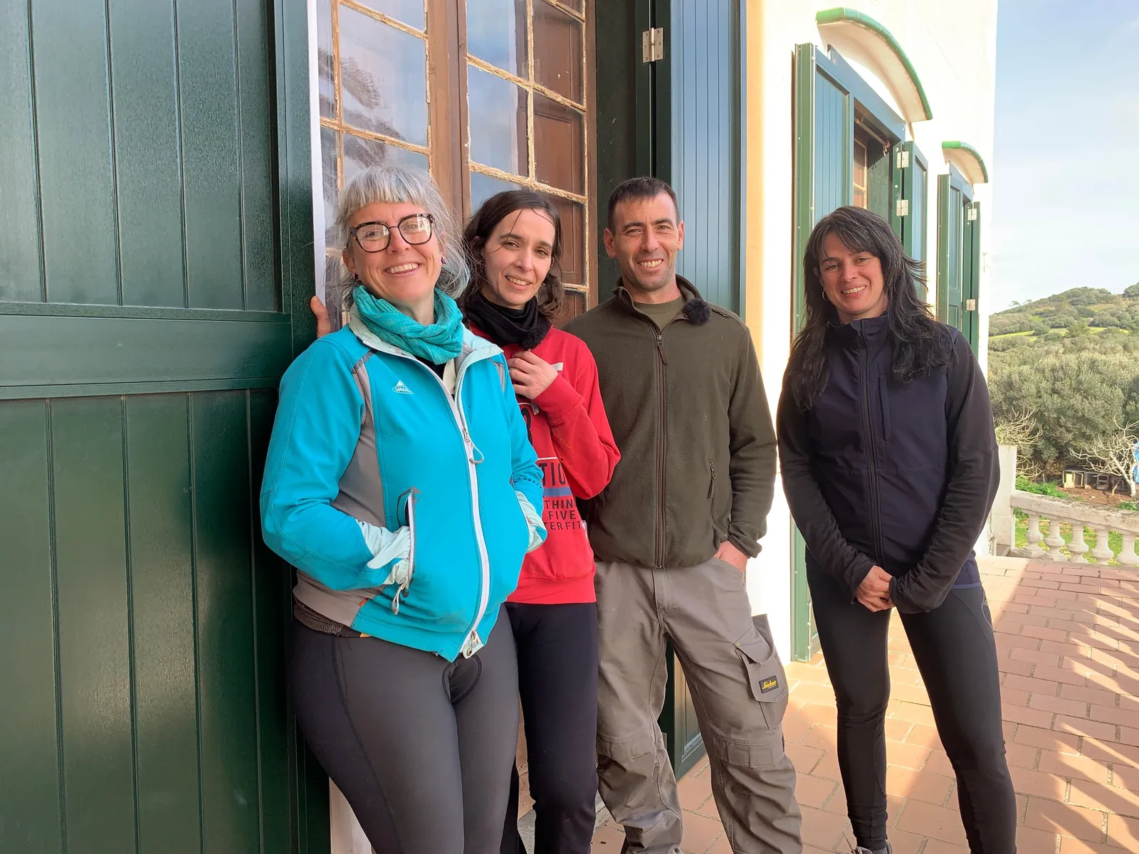 Cuatro personas posando en la puerta de una casa señorial